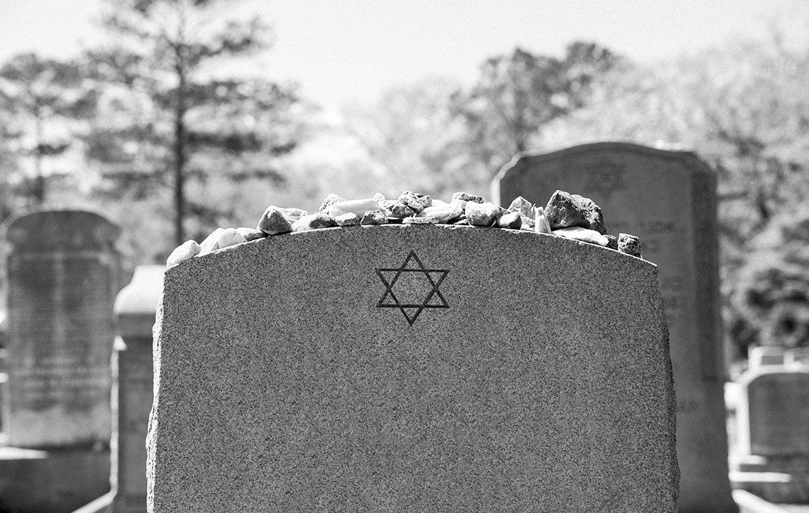 Jewish gravestone engraved with a Star of David, with memorial stones left by mourners.