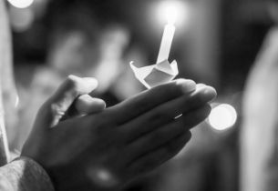 Hands holding a candle at a memorial vigil, symbolizing a personalized celebration of life service honoring a loved one.