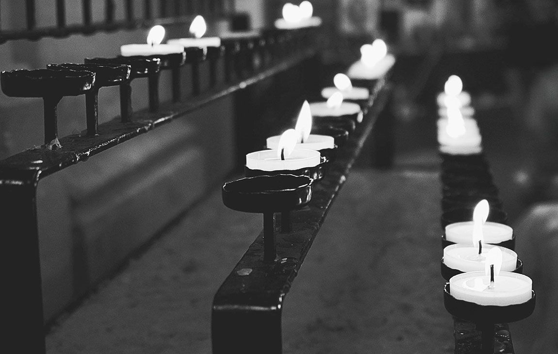 Lit candles in a place of worship, symbolizing remembrance and spiritual reflection.