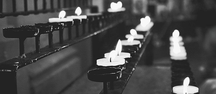 Lit candles in a place of worship, symbolizing remembrance and spiritual reflection.