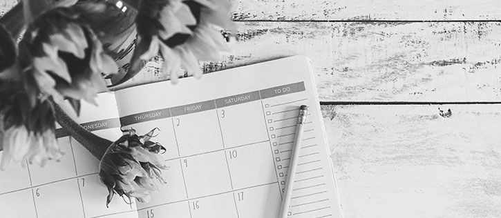 Open calendar with a pencil and flowers, symbolizing the planning involved in funeral arrangements.