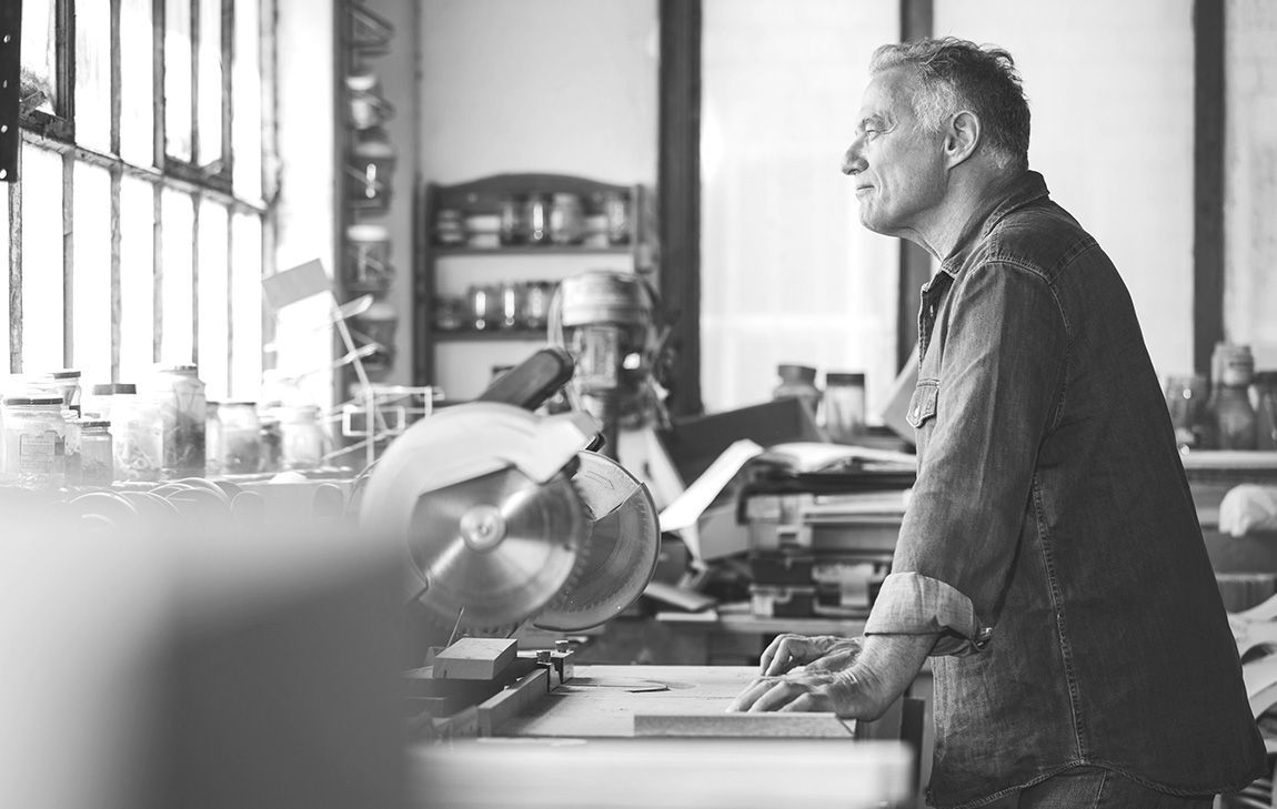 An older man in his woodshop, looks thoughtful while reflecting on his life