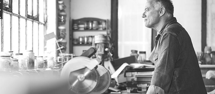 An older man in his woodshop, looks thoughtful while reflecting on his life