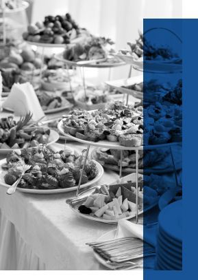 A black-and-white view of a banquet table with a variety of catered dishes on it for a funeral reception
