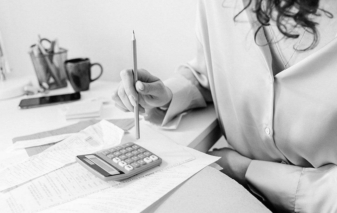 A woman with a calculator and pencil tallying the cost of funeral expenses