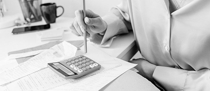 A woman with a calculator and pencil tallying the cost of funeral expenses