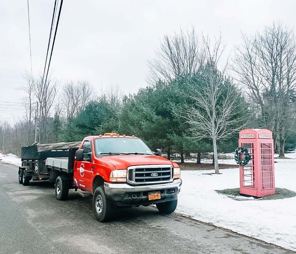 A red truck is parked on the side of the road next to a red telephone booth
