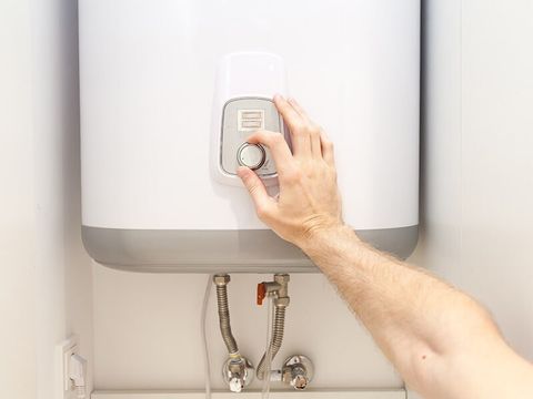 Man Adjusting The Heat Of Hot Water System — Brian Cook Plumbing in Coffs Harbour, NSW