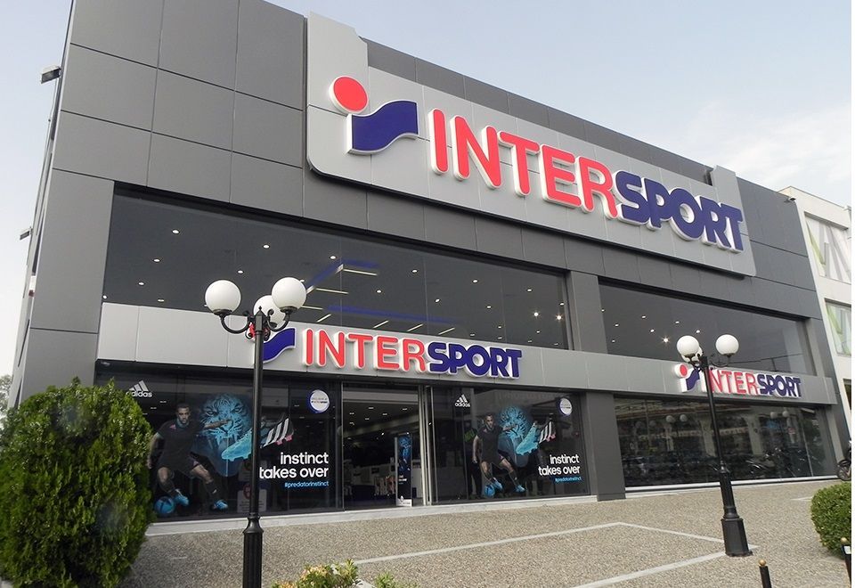 Exterior of an INTERSPORT store with large windows, gray facade, and the brand's logo above the entrance.