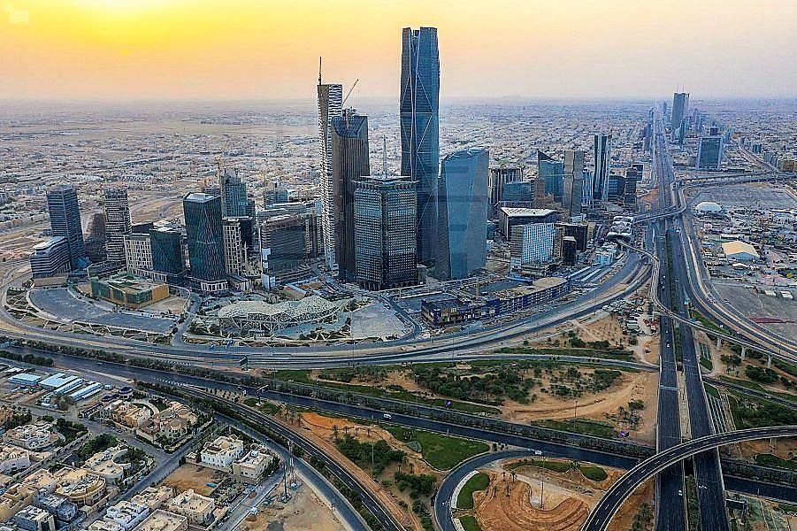 City skyline with tall buildings, roads, and bridges under a sunset sky in the desert.