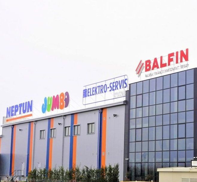 Building with signs: NEPTUN, JUMBO, ELEKTRO-SERVIS, BALFIN in bold colors.