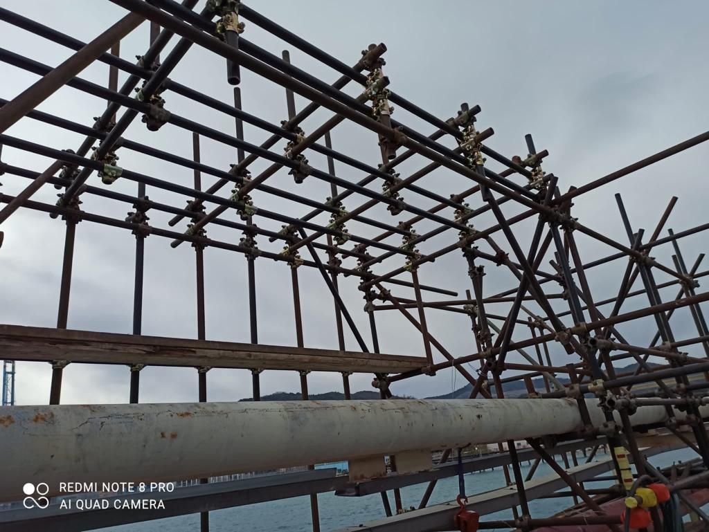 Costruzione di un'impalcatura su una struttura, potenzialmente un molo o un ponte, con cielo coperto.