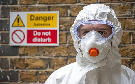 Asbestos specialist wearing his safety mask and uniform