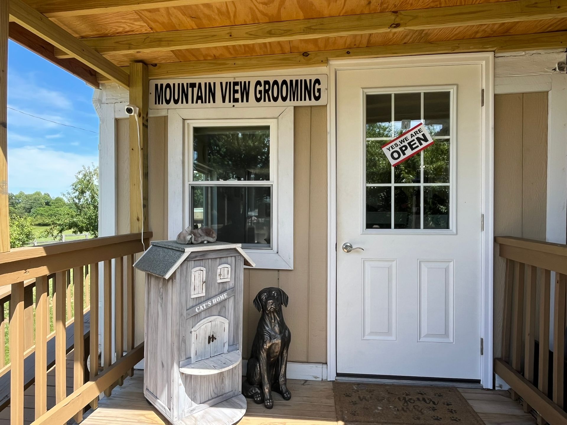 A dog statue is sitting on the porch of a mountain view grooming shop.