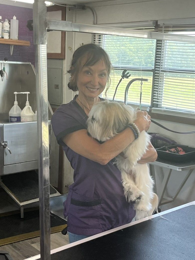 A woman is holding a small white dog in her arms.