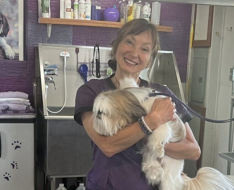 A woman is holding a small dog in her arms and smiling