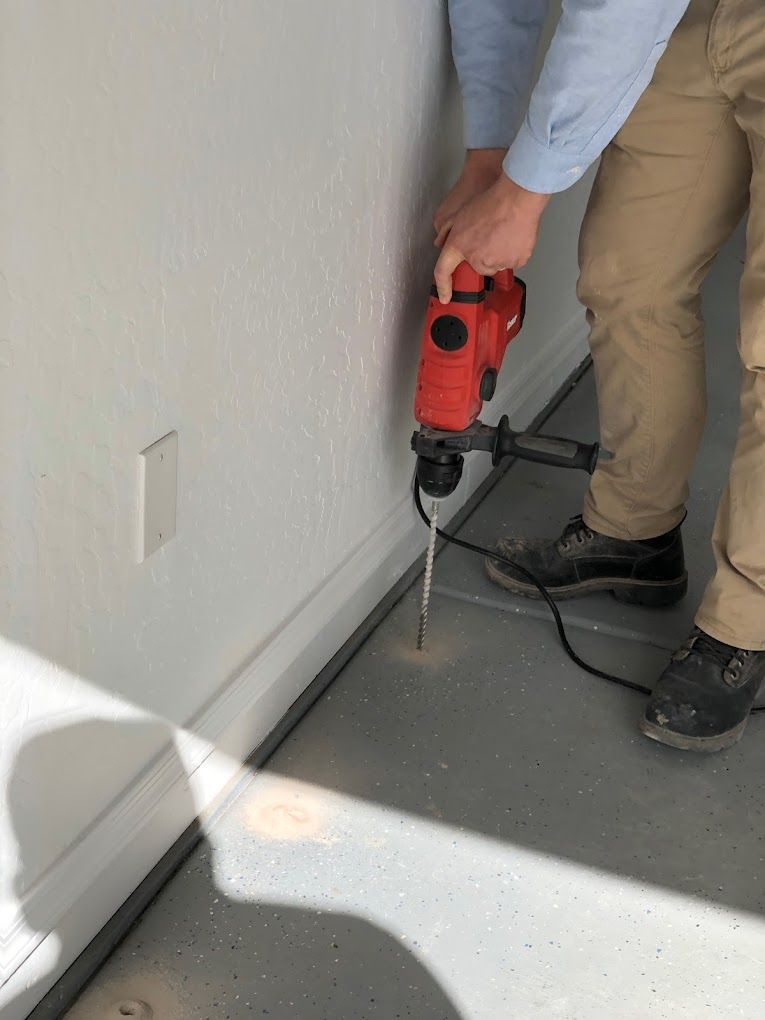 A man is using a hammer to drill a hole in a wall.