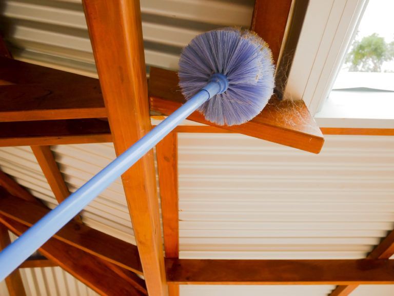 A blue broom is hanging from a wooden ceiling