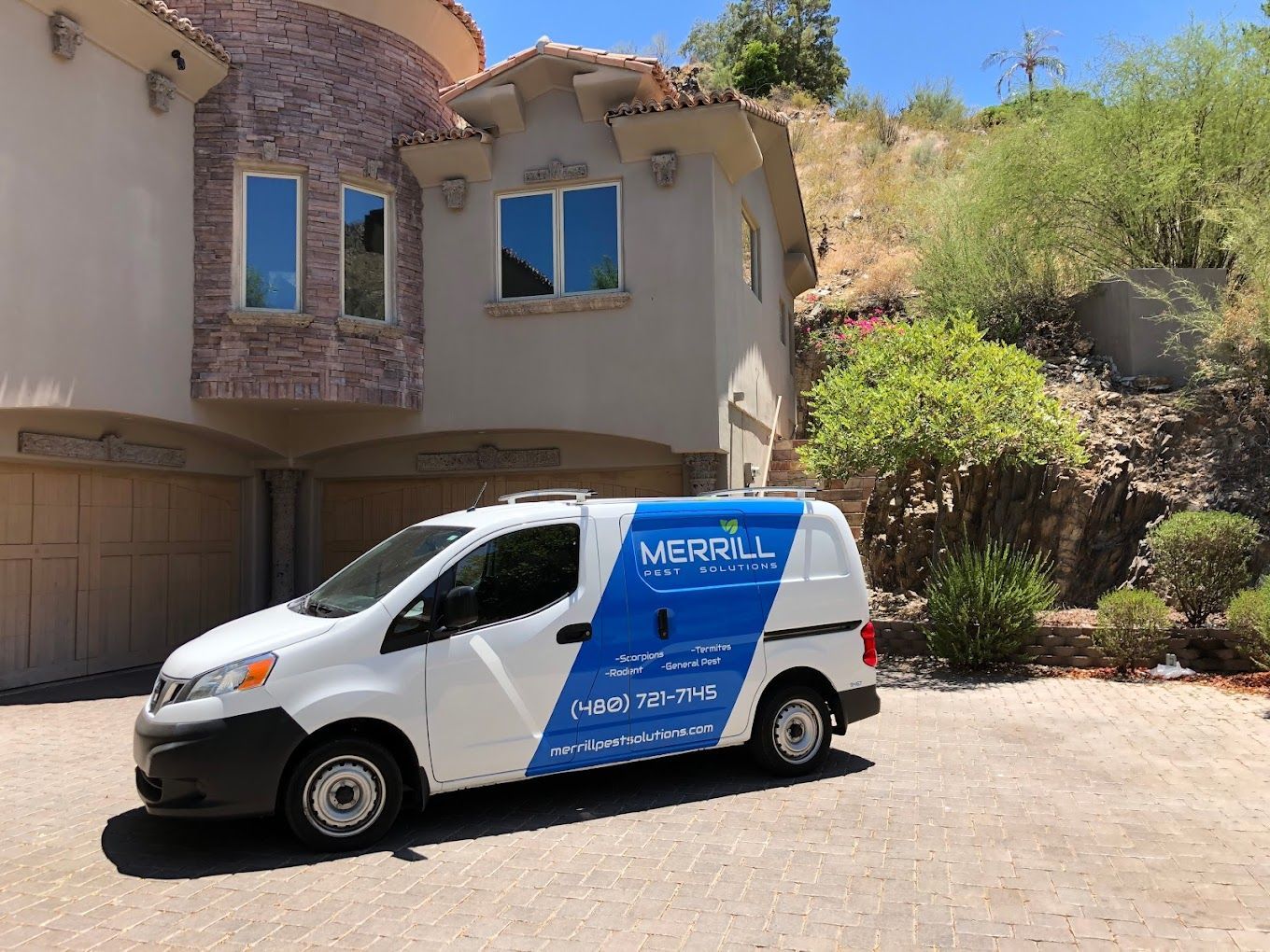 A white van is parked in front of a large house.
