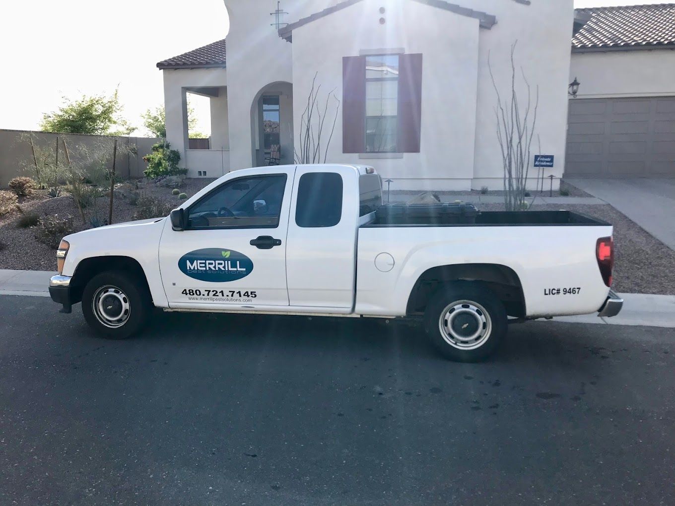 A white truck is parked in front of a white house.