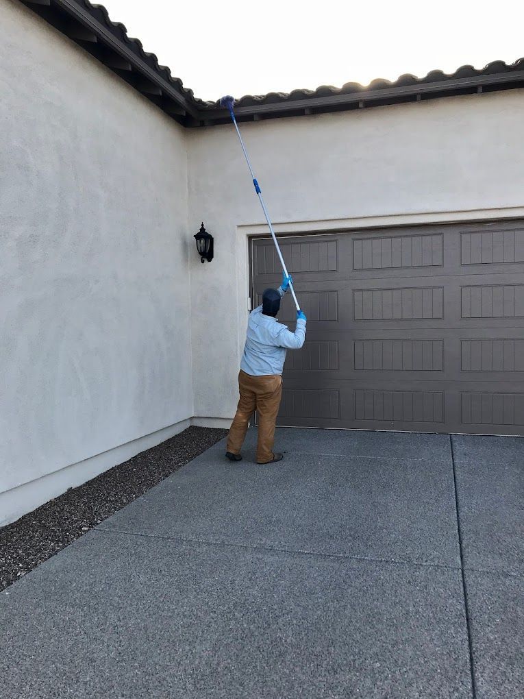 A man is cleaning a garage door with a long pole.