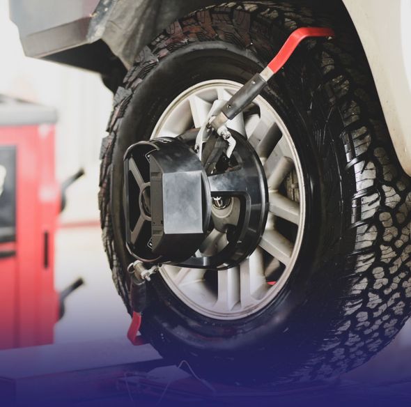 Tire clamp on a car wheel in a workshop, with a red strap attached. | Mario’s Automotive