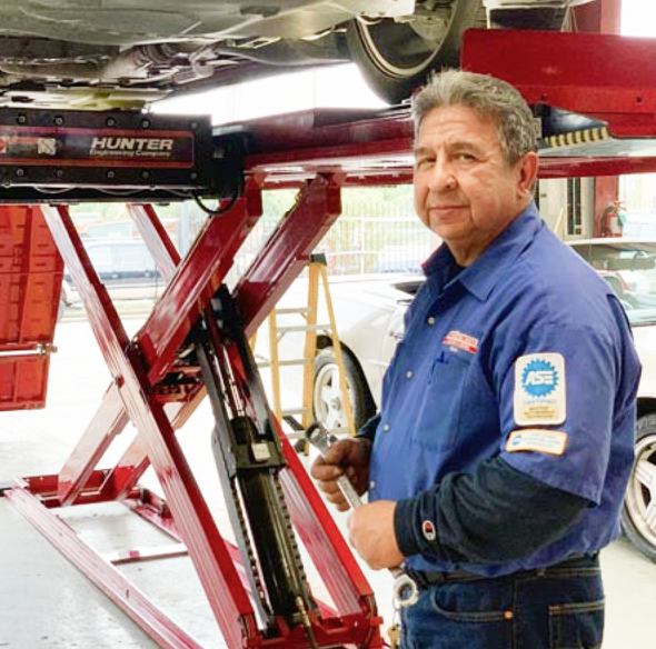 Mechanic in blue shirt beside red car lift in an auto repair shop | Mario’s Automotive
