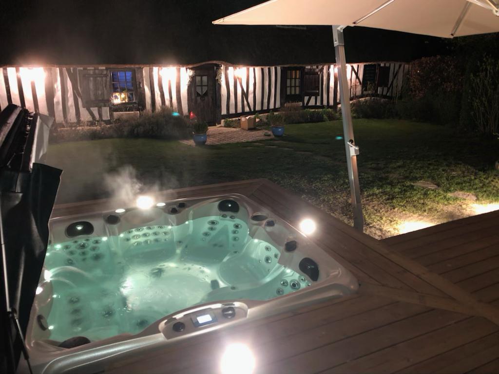 Un jacuzzi est éclairé la nuit sur une terrasse.