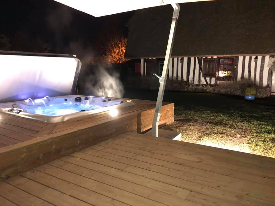 Un bain à remous est posé sur une terrasse en bois la nuit.