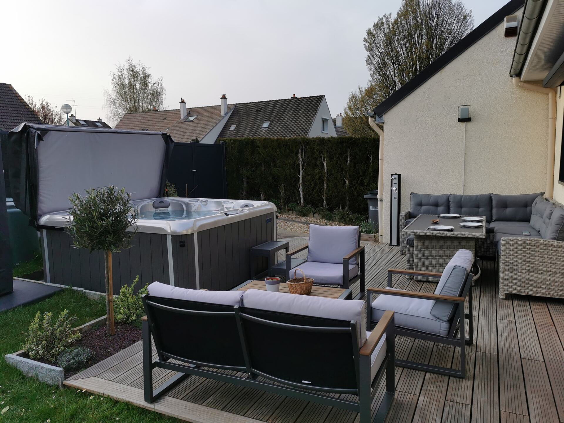 Il y a un bain à remous dans l'arrière-cour avec un canapé et des chaises.