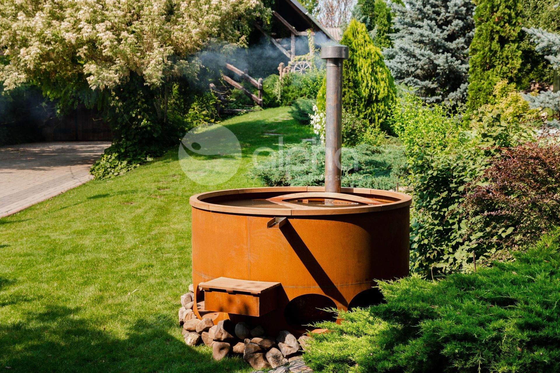 Une baignoire en métal rouillée se trouve au milieu d'un jardin verdoyant.