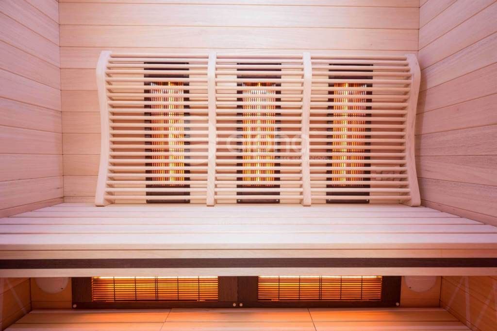 Un banc en bois dans un sauna avec une rangée de lumières sur le mur.