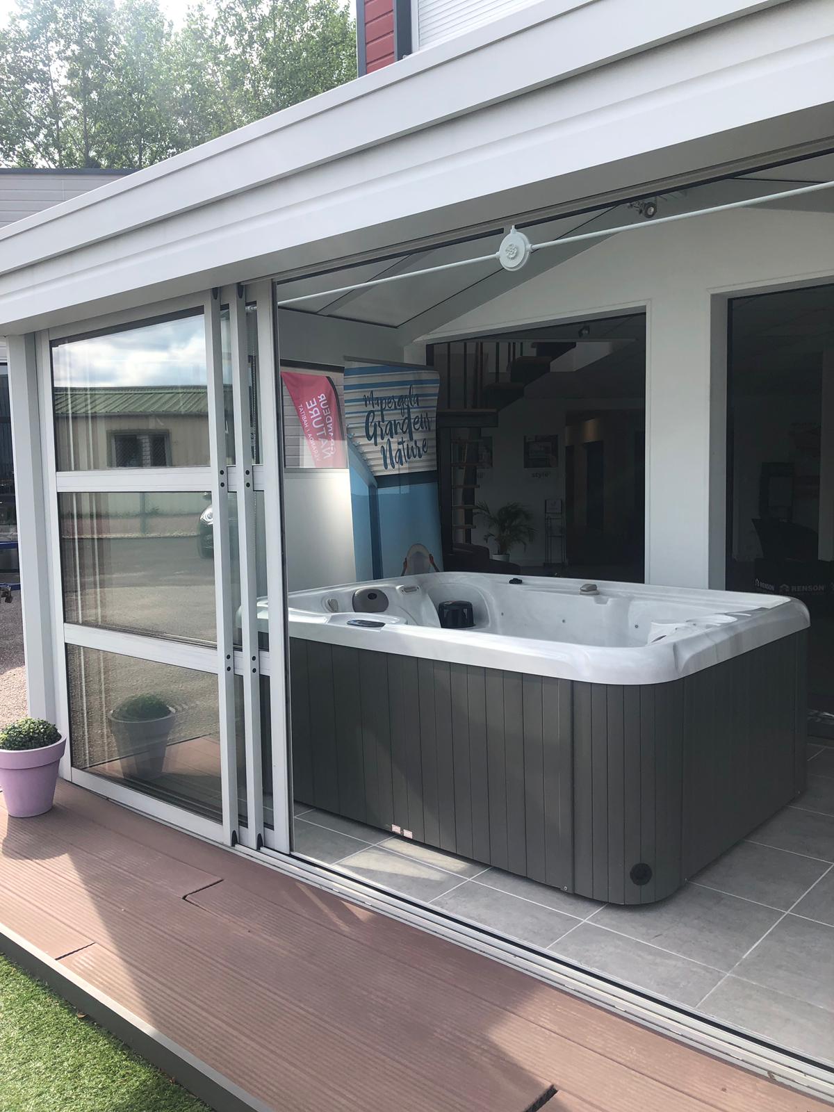 Un bain à remous est installé à l'extérieur d'une maison avec des portes coulissantes en verre.