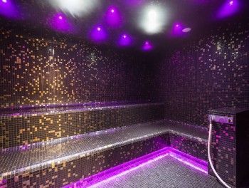 Un hammam violet et or avec des lumières violettes au plafond.