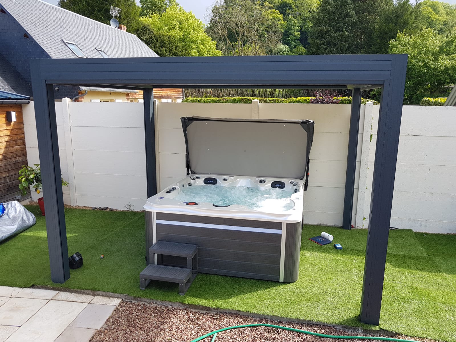 Un bain à remous est installé sous une pergola dans une cour arrière.