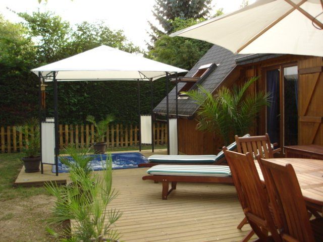 Une terrasse en bois avec des chaises et des parasols devant une maison