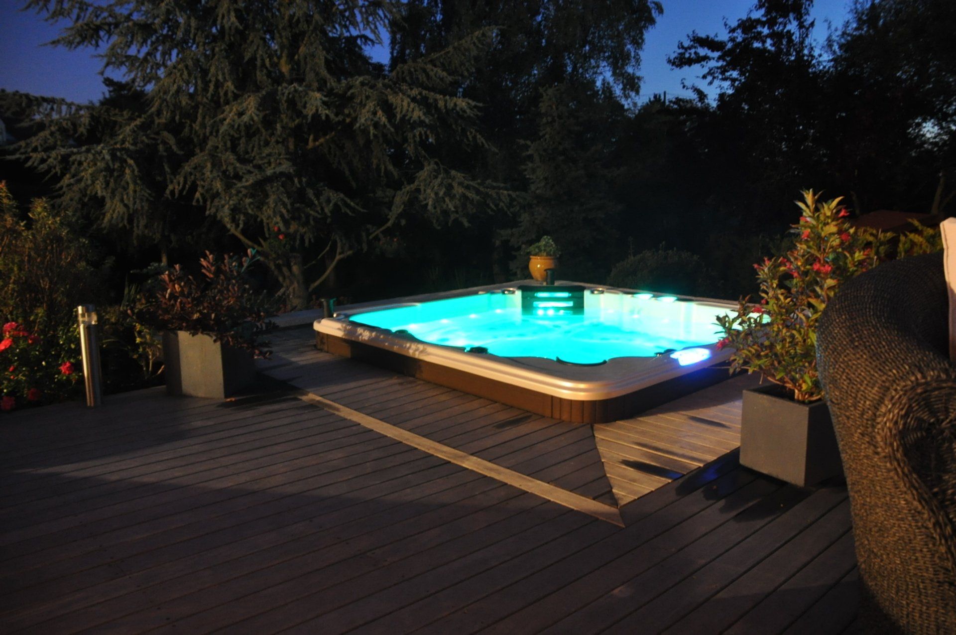 Un jacuzzi est éclairé la nuit sur une terrasse
