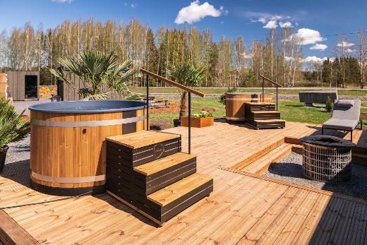 Un bain à remous en bois est posé sur une terrasse en bois.