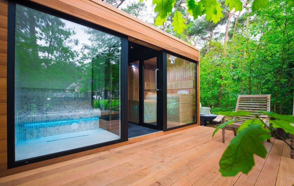 Une maison en bois avec une grande porte vitrée et une piscine dans l'arrière-cour.