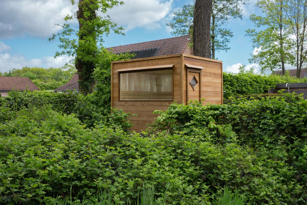 Unsauna en bois est entouré d'arbres et de buissons.