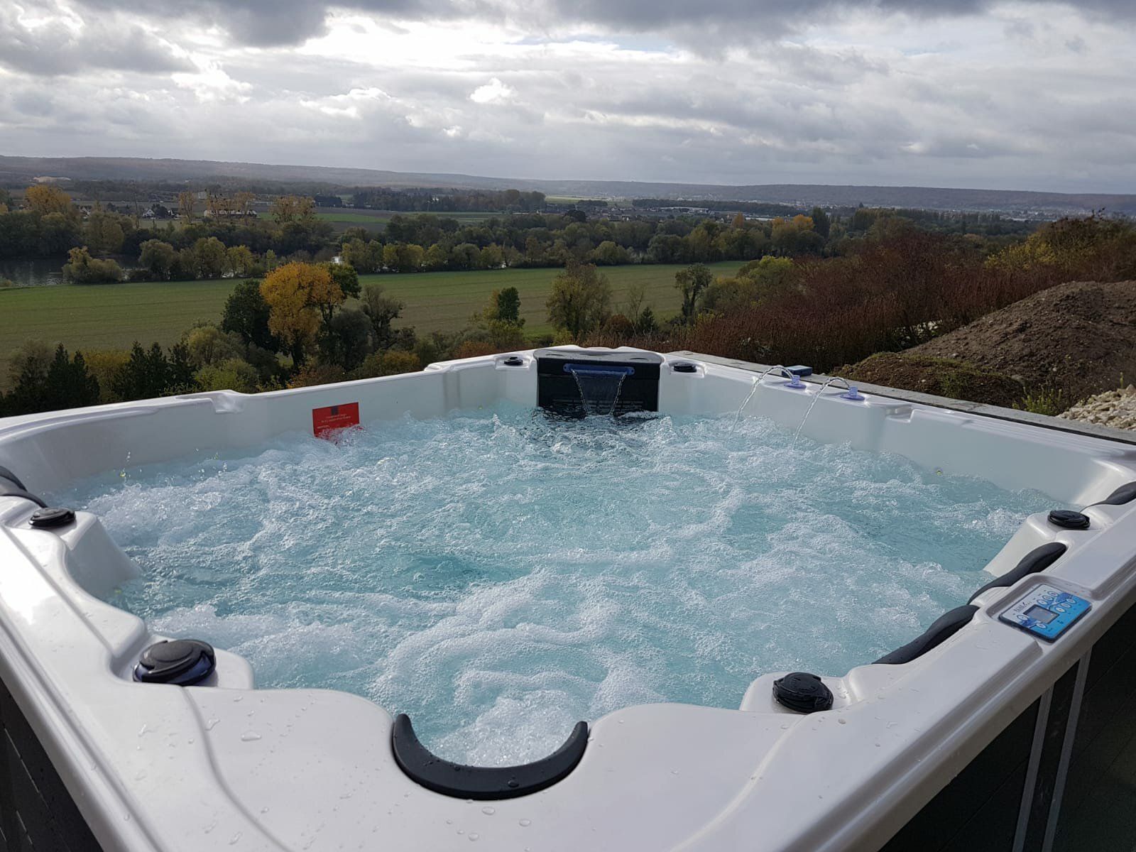 Un bain à remous avec vue sur un champ et des arbres en arrière-plan.