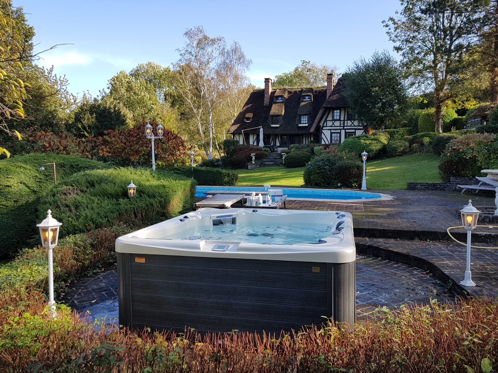 Un jacuzzi est installé au milieu d'un jardin devant une maison.