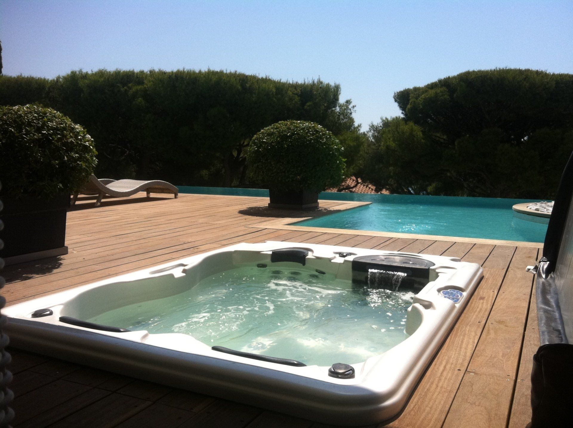 Un bain à remous est installé sur une terrasse à côté d'une piscine