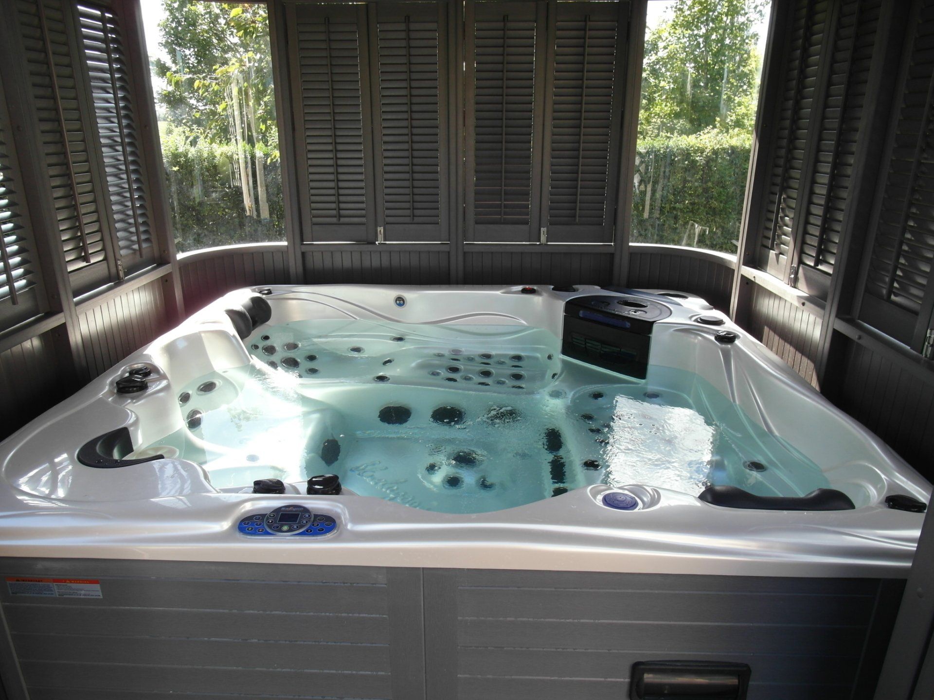 Un grand bain à remous est installé à l'intérieur d'un bâtiment avec des volets.