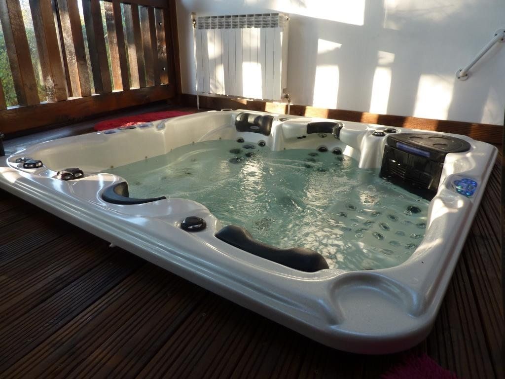 Un grand bain à remous est posé sur une terrasse en bois