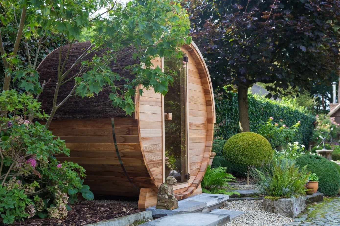Un tonneau en bois est posé au milieu d'un jardin entouré d'arbres.