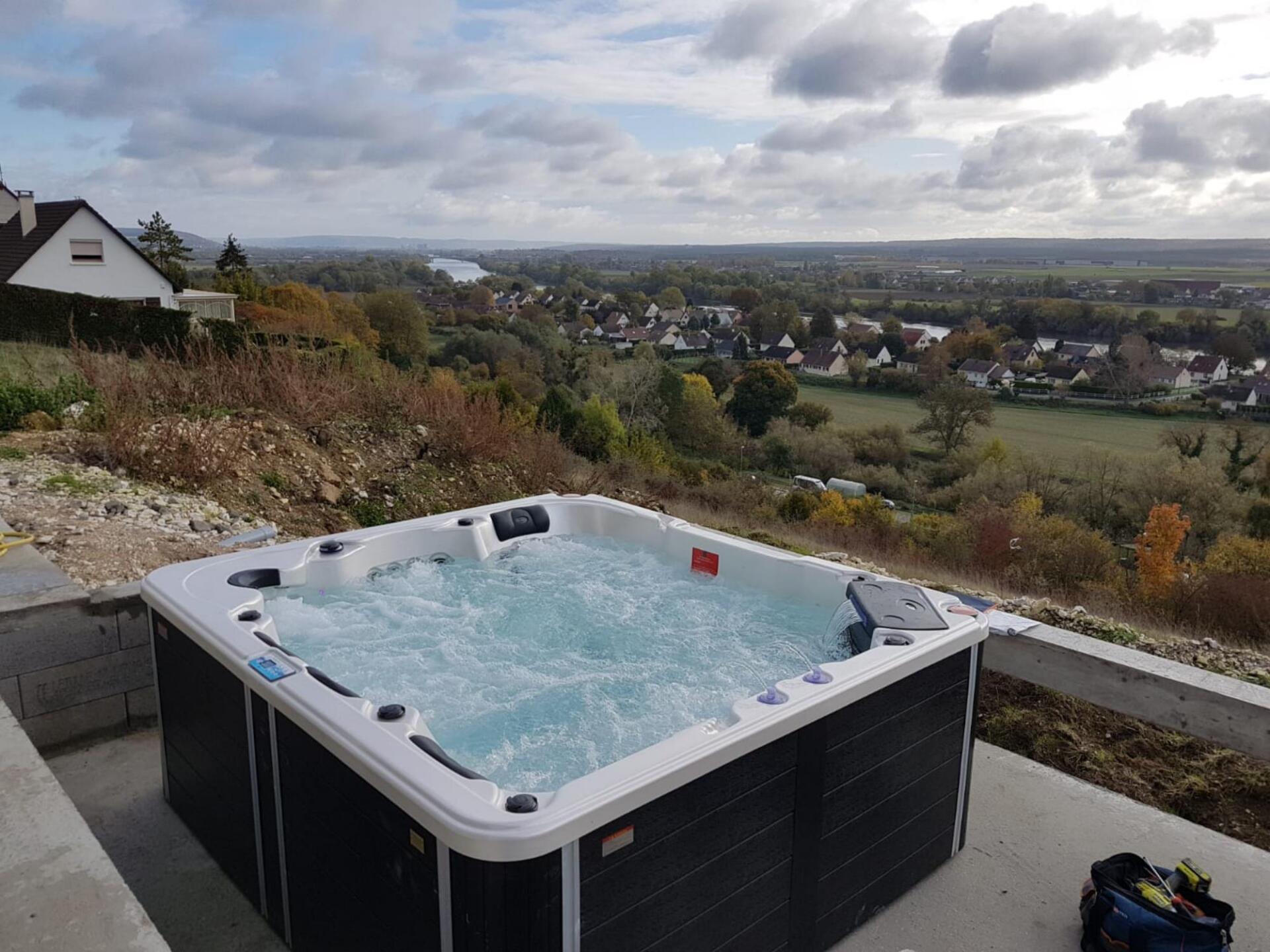 Un bain à remous est posé sur une terrasse en béton avec vue sur la ville.