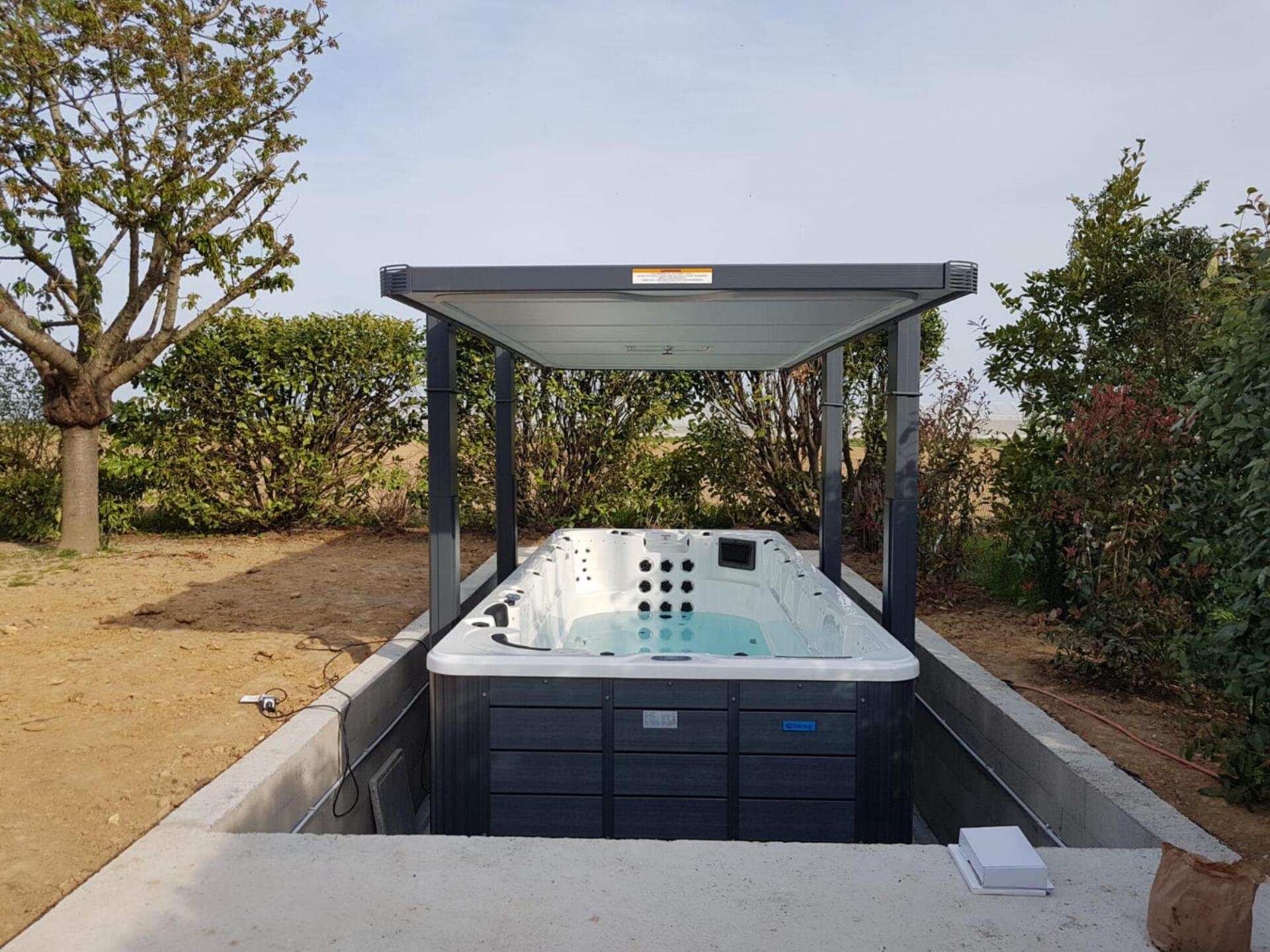 Un bain à remous est installé sous un auvent au milieu d'un jardin.
