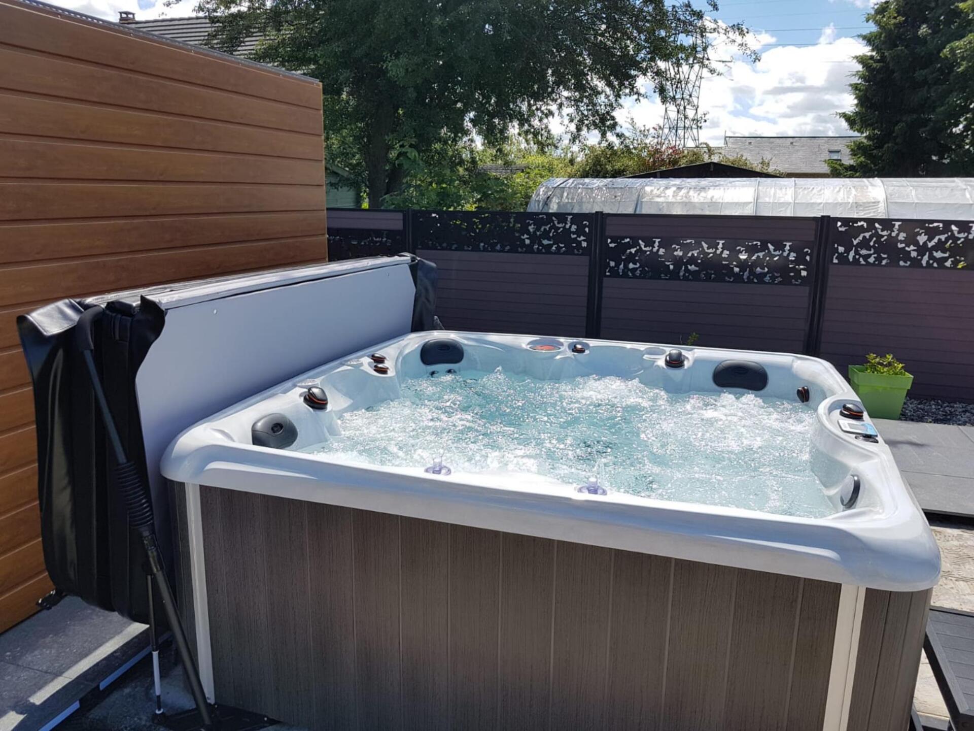 Un bain à remous est installé dans l'arrière-cour à côté d'une clôture en bois.