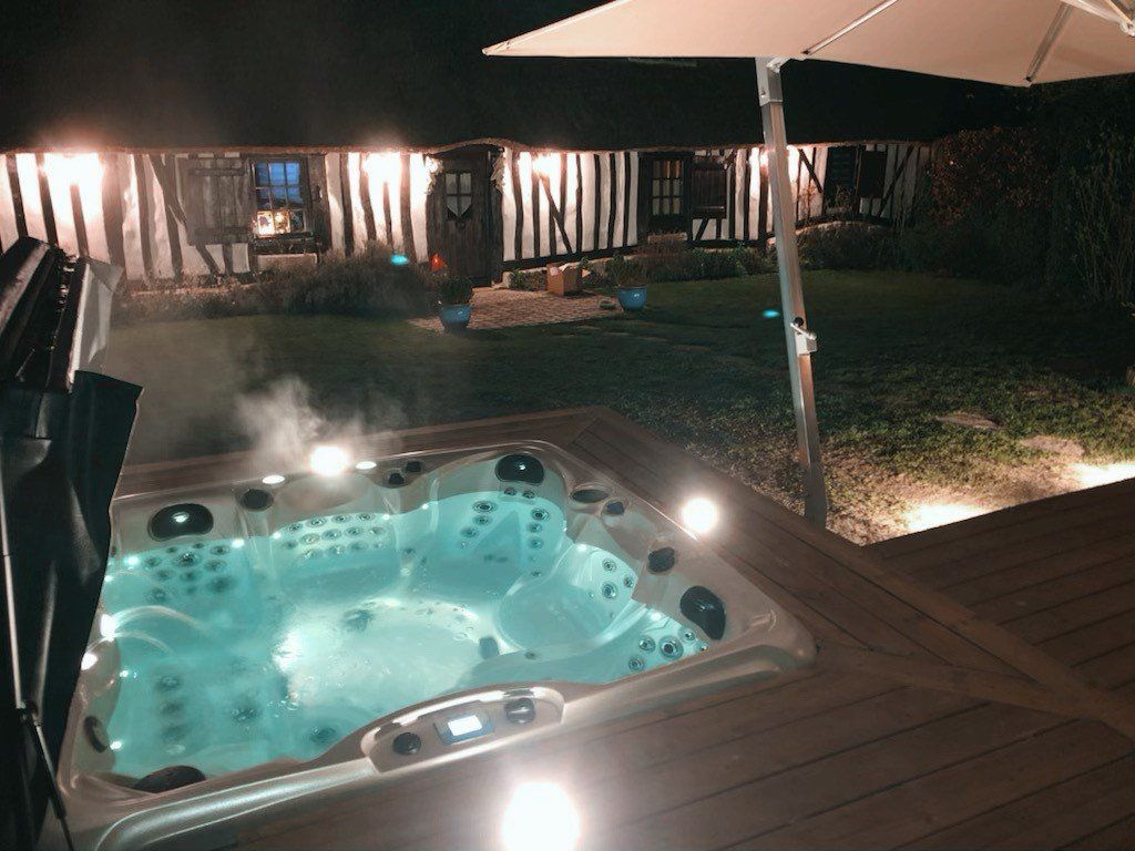 Un jacuzzi est éclairé la nuit sur une terrasse